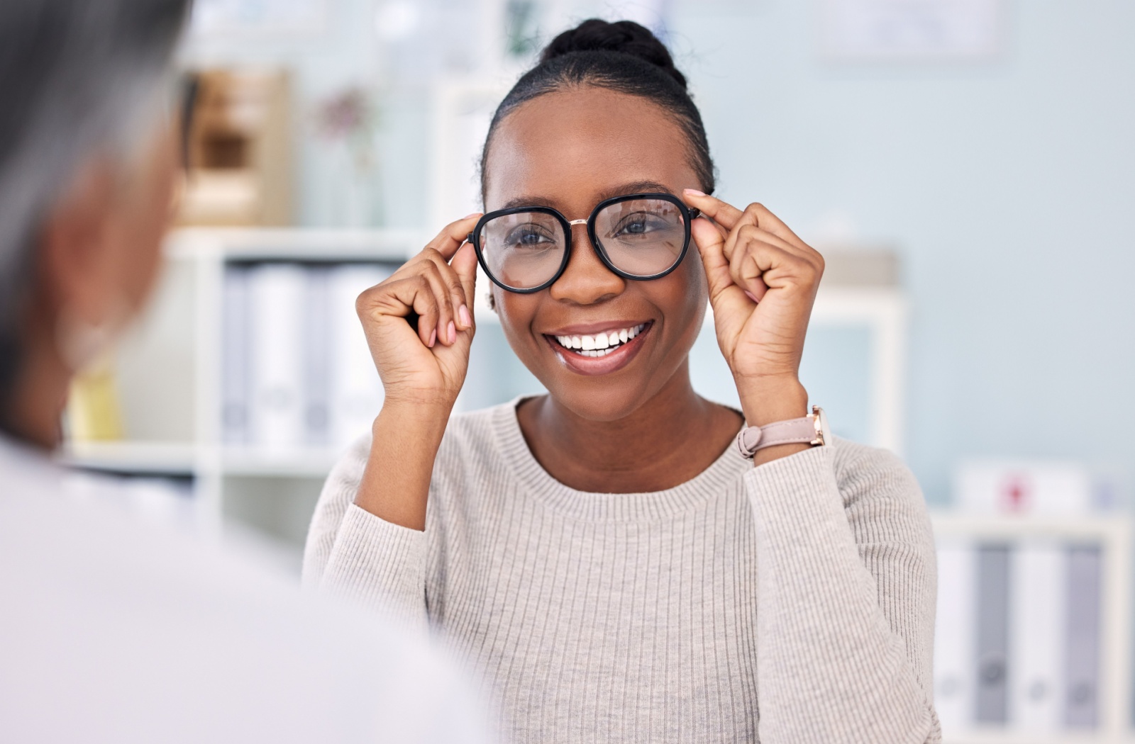 Smiling woman trying on new eyeglasses during an eye exam.